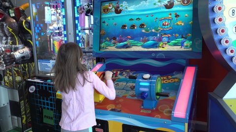 Fishing game. Little girl in the entertainment center. The child plays on token ticket slot machines. She won a big bonus. Perm, Russia, March 31-2022