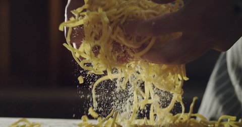 Cinematic close up shot of professional artisan baker chef is preparing homemade egg pasta of fresh ingredients in rustic bakery kitchen.