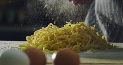 Cinematic close up shot of professional artisan baker chef is preparing homemade egg pasta of fresh ingredients in rustic bakery kitchen.