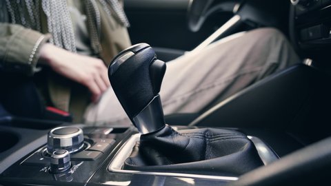 Close-up of a white woman hand in casual clothes at the wheel of a car, shifting gears in auto. European girl drives an automobile.auto, automatic, box, car, change, clutch, confidence, dashboard, dri