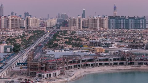 Jumeirah Palm island day to night transition aerial timelapse after sunset in Dubai, UAE. Villas and monorail train top view from above. Jumeirah Palm is artificial and unique island in Dubai with