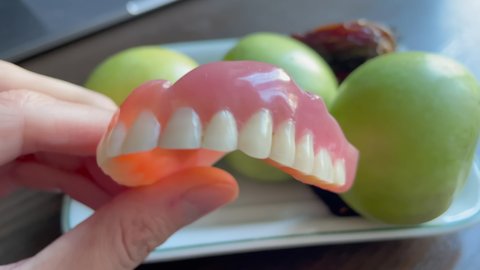 Human denture of the upper jaw in the hand. Used acrylic denture. Video of a Set of false teeth in a women's hand.