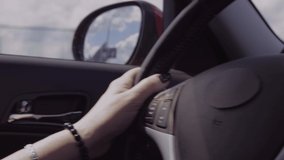 Video, a woman is driving a auto, her hands are on the steering wheel, the sun is shining.