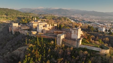 Great sunset view of arabic fortress Alhambra in Granada. Aerial view of Alhambra with snowy mountains background. Andalusia, Spain