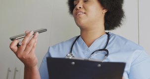 Video of focused plus size african american female doctor using smartphone. health, medicine and doctor profession.