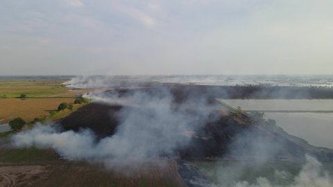 Aerial footage over a charred farmland after being burnt while the smoke is still rising, Grassland Burning, Pak Pli, Nakhon Nayok, Thailand.