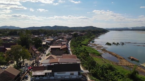 Aerial footage sliding to the right revealing the Walking Street in Chiang Khan then Laos with Mekong River, Loei in Thailand.