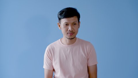 4K 50fps, Asian man mustache,Half of the young man's nose itches and sneezes out, and uses a white tissue to wash out what comes out of his nose.Isolated indoor studio on blue background.
