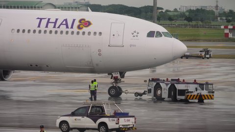 BANGKOK, THAILAND - NOVEMBER 11, 2017: Middle shot, Airbus A330 Thai Airways towing a tractor to the runway at Suvarnabhumi Airport. Tourism and travel concept