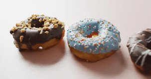 Video of donuts with icing on white background. colourful fun food, candy, snacks and sweets concept.