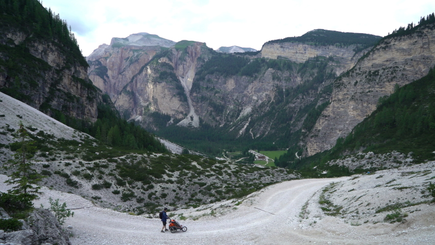 Man with his child in a bicycle trailer walking in the mountains, Dolomites, Italy

