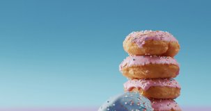 Video of donuts with icing on pink and blue background. colourful fun food, candy, snacks and sweets concept.