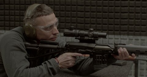 A man fires a Dragunov sniper rifle. Glasses on the eyes. Ears are covered with earmuffs. The sleeve flies out through the bolt. Shooting training. CZ, Prague, Zlicin, 30.3.22