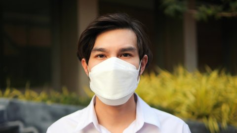 Young Asian man emotionally takes off medical safety mask. High quality 4K footage concept of Covid19, epidemic, air pollution. Thailand.