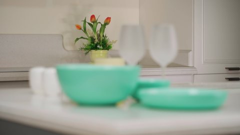 Dinner table setting. Green plates and wine glasses stand on the table. Set of utensils for dinner. Defocus from the background to the foreground
