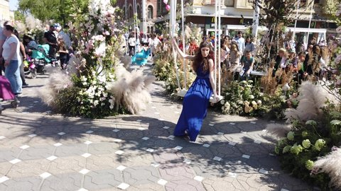 TIMISOARA, ROMANIA - April 20, 2019: TIMFLORALIS international flower festival. Woman wearing a long blue dress is enjoying the flower decorations in the city center