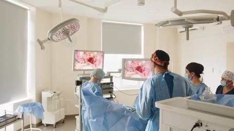 Laparoscopic surgeon looking at monitor during laparoscopic surgery. Process of gynecological surgery operation using laparoscopic equipment. Group of surgeons in operating room with surgery equipment