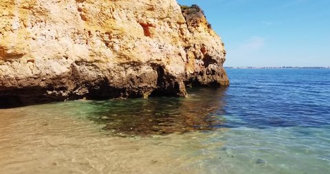 Relax on an empty sea beach. Golden rocky coastline with crystal blue water. No people. Calm water with high cliff and rocky mountain. Deep blue sea o a sunny summer day. Golden beach. Tropical 