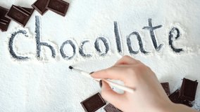 International Chocolate Day. The girl writes with a brush on sugar congratulations on chocolate day. Chocolate Day. World Postcard with chocolates. Horizontal video.