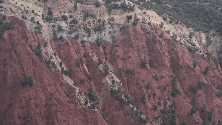 Majestic sandstone hill side with growing trees in Morocco, handheld view