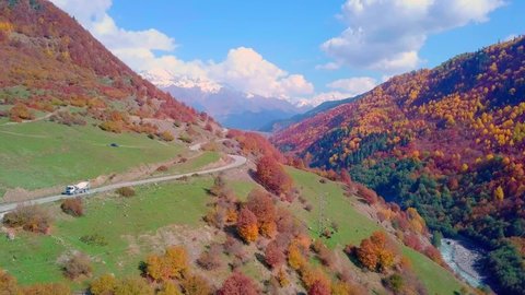Flying on drone over autumn mountains with serpentine mountain road and forest. Georgia, Svaneti. drone flies over beautiful landscape autumn colorful forest, dangerous road for professional drivers