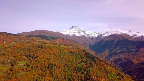 Epic aerial drone flight over mountains in autumn, sunset, colorful autumn trees, color of golden hour. Georgia, Svaneti region. Yellow, red and green leaves on trees. Colorful leaves in mountains.