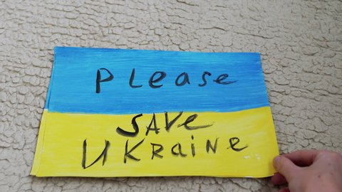 Female Hands Lay Out Drawings on the Floor with Inscriptions Stop War in Ukraine. Messages on the banner with an appeal to confront the military conflict on poster of the blue-yellow flag of Ukraine.