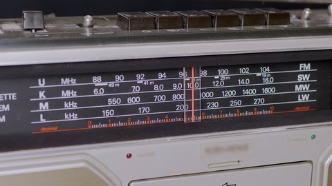 Tuning the Frequency, Searching Wave on an Old Vintage Analog Radio. Search for a music radio station on a dial scale on panel of a short-wave portable FM receiver, player, tape recorder 80s, 90s.