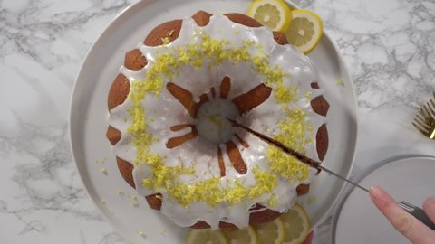 Flat lay. Step by step. Slicing lemon bundt cake decorated with lemon zest on a cake stand.