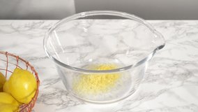 Time lapse. Step by step. Zesting fresh lemons into a glass mixing bowl to prepare lemon bundt cake.