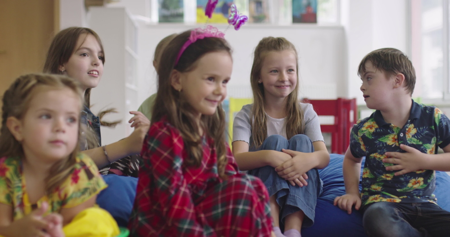 Storytime elementary or primary school teacher reading a story to a group of children in a daycare center.  Royalty-Free Stock Footage #1088848823