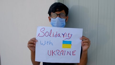 Young protesters protest against Russia and in favor of Ukraine, A young protester holding a banner is protesting against Russia and in favor of Ukraine, Ukraine vs Russia war, solidarity with Ukraine
