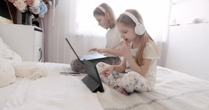 Children play online. Video call and chat with a preschooler. Kids girls using digital tablet and headphone. Cute kids use laptops for education, online study, home study, kids learn language online.