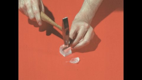1960s: Man holds razor blade above crystal, taps it with hammer, splits crystal apart.