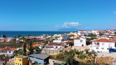 Fly over the village in the region of Malaga Andalusia Benajarafe Spain. Village of white houses on the shores of the Mediterranean Sea. Mediterranean landscape with beach and sunset. Malaga Spain