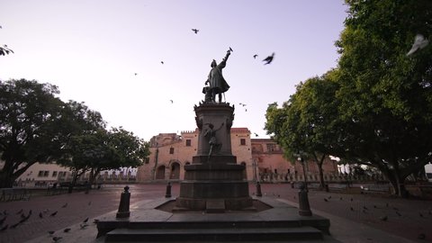Dominican Republic, Santo Domingo - January 28, 2022: Monument to Christopher Columbus in Columbus Park, Colonial Zone with no people at down. Slow motion of pigeons fly to camera in the foreground. 