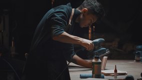 Side view cinematic video of a carpenter at work in a carpentry workshop. The guy polishes wooden parts with a grinder. Dark key, male hobby, family carpentry business.