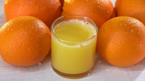 Fresh orange juicein a glass with many orange fruit. Top view. White wooden table. Heathy