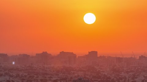 Sunset in Ajman aerial view from rooftop timelapse. Evening view of big sun on orange sky in the United Arab Emirates.