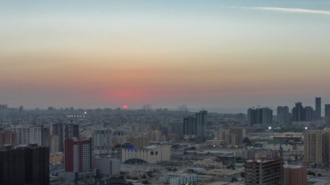 Cityscape of Ajman from rooftop from day to night transition timelapse after sunset. Ajman is the capital of the emirate of Ajman in the United Arab Emirates.
