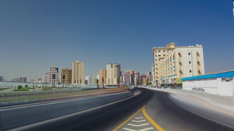 Road traffic in Ajman, view from bridge at day timelapse hyperlapse. Urban cityscape with towers on a background in the United Arab Emirates.