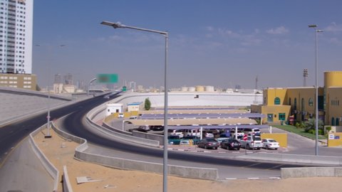 Road traffic on overpass in Ajman, view from bridge at day aerial timelapse hyperlapse. Urban cityscape with towers on a background in the United Arab Emirates.