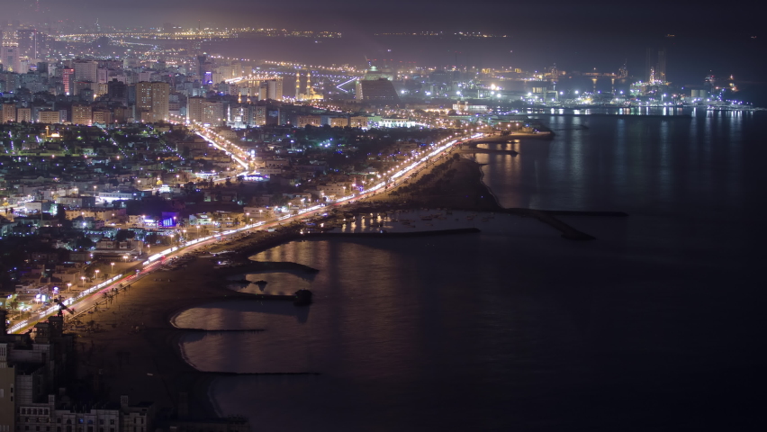 Panoramic view of Sharjah coastline at night from Ajman rooftop timelapse - third largest and most populous city in United Arab Emirates. Sharjah is located along northern coast of Persian Gulf on