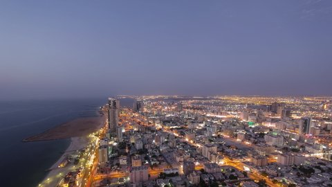 Cityscape of Ajman from rooftop from day to nigh transition aerial timelapse after sunset. Ajman is the capital of the emirate of Ajman in the United Arab Emirates.