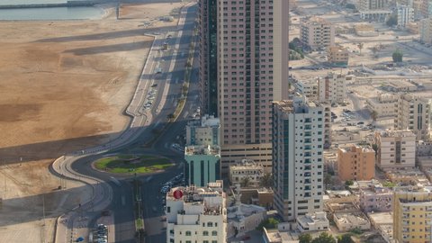 Cityscape of Ajman with old ship and traffic on road intersection from rooftop morning after sunrise with long shadows timelapse. Ajman is the capital of the emirate of Ajman in the United Arab
