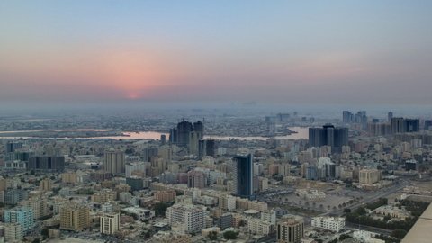 Sunrise with cityscape of Ajman from rooftop aerial timelapse. Sun over modern city. Ajman is the capital of the emirate of Ajman in the United Arab Emirates.