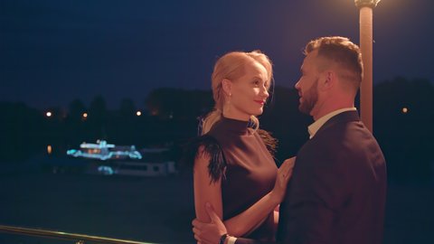 Close up of romantic couple looking in each other's eyes and kissing outdoors in evening. Attractive male and female sharing tender kiss outside at night. 4k. High quality 4k footage