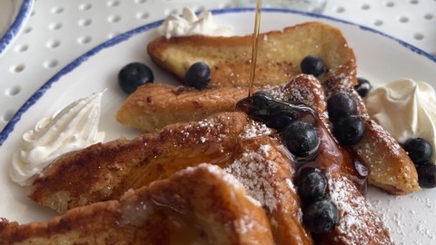 Maple syrup is poured on French toast in slow motion.