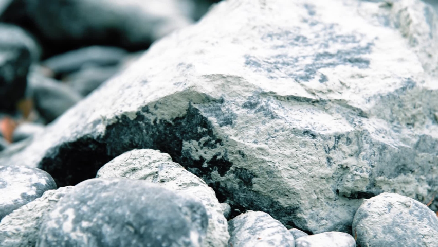Motorised dolly slider shot of the splashing water in a mountain river, with rocks and yellow leaves. Horizontal steady movement at overcast cloudy autumn weather.