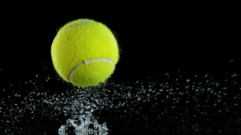 Super slow motion of falling tenis ball on water surface, black background.